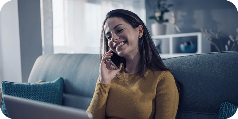 Mulher sorrindo em ligação no telefone, simulando uma compra de imóvel com precatório