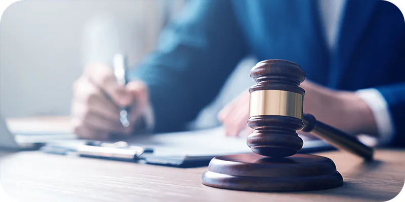 Assinatura de documento jurídico sobre mesa com martelo de juiz em primeiro plano, ilustrando a expedição de ofício