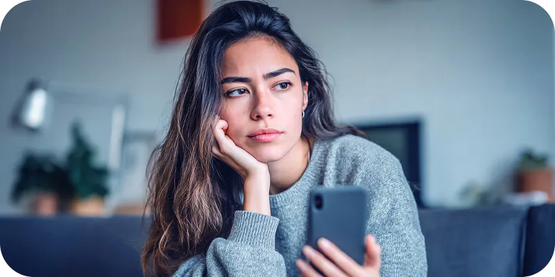 Mulher pensativa segurando o celular, ilustrando a possibilidade de antecipação de precatório