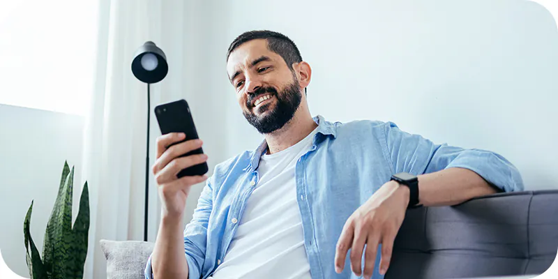 Homem sorridente usando o celular, ilustrando a doação de parte do imposto