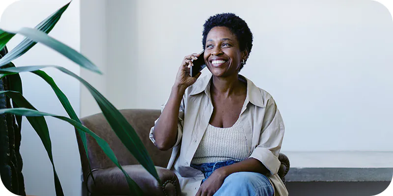 Mulher sorrindo ao telefone, ilustrando a tirada de dúvidas sobre doação de parte do imposto