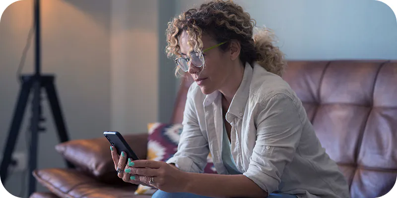 Mulher analisando celular, ilustrando pesquisa se INSS paga o tempo de espera pela perícia